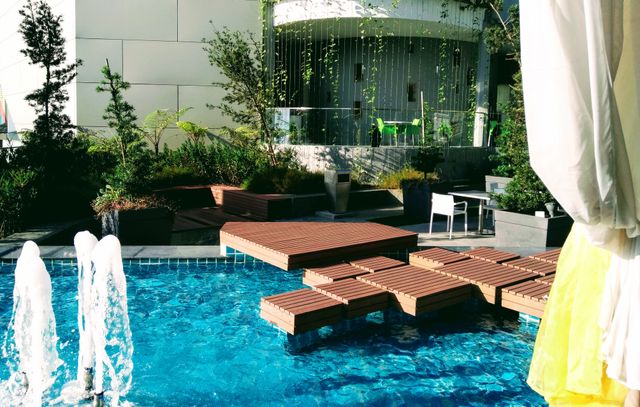 A luxurious outdoor pool area with stylish decking and a beautiful fountain, perfect for relaxation